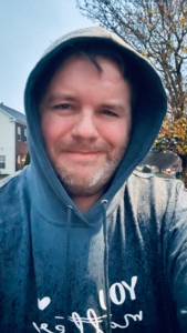 image of Matthew Ross in a hoodie sweatshirt walking in the rain